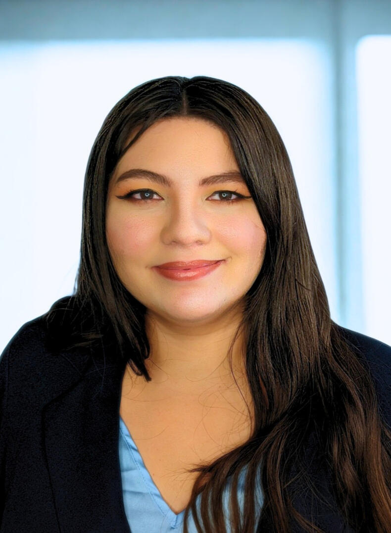 Carol Estrada the Graphic Gal, wearing a dark jacket and blue shirt, she has long dark hair